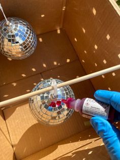 a person in blue gloves is spraying something with a pink liquid into a disco ball