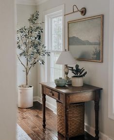 a living room with a table, potted plant and lamp on the side wall