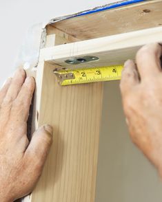 a man measuring the width of a piece of wood with a tape measure ruler on it