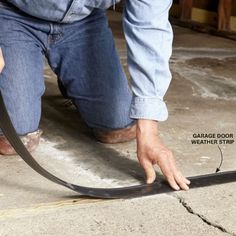 a man is using a hose to fix a garage door seal on the concrete floor