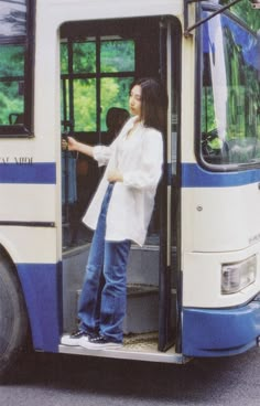 a woman standing on the door of a bus with her hands in the open window