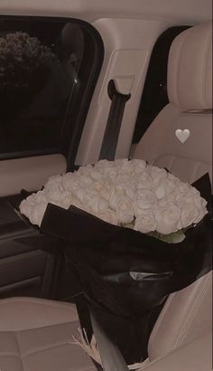 a bouquet of white roses in the back seat of a car with hearts on it