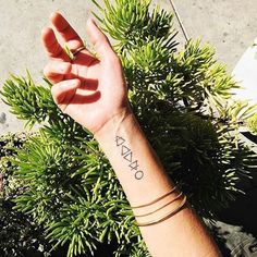 a person's arm with the word raw on it, in front of some plants