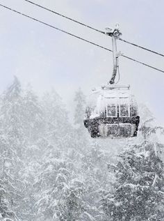 a snow covered ski lift with trees in the background