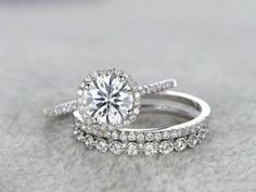 two wedding rings on top of each other, one with a large diamond in the center