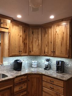 a kitchen with wooden cabinets and granite counter tops, along with a coffee maker on the corner