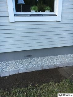 the side of a house with grass and gravel