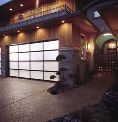 a large garage door is lit up in front of a house at night with lights on