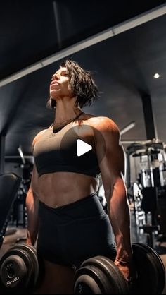 a woman in a black sports bra top is holding two dumbbells