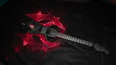 an electric guitar with red lights on it's head and neck, laying on a black cloth