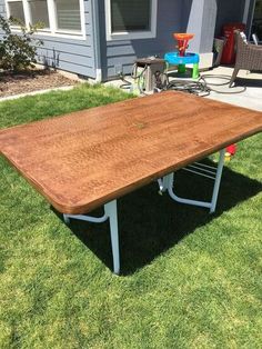 a wooden table sitting on top of a lush green field in front of a house