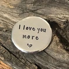 i love you more pin sitting on top of a piece of wood