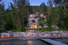 a house is lit up at night on the water's edge near a dock