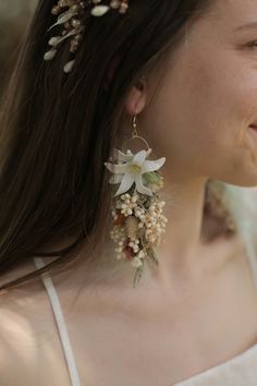 a close up of a person wearing earrings with flowers on the back of their ear