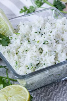 rice in a glass dish with lime wedges and cilantro on the side