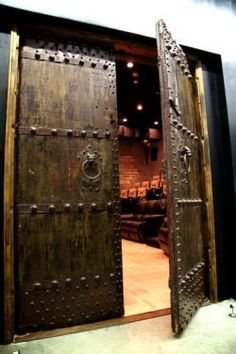 an open wooden door with metal studs on the outside and inside, in front of a stage