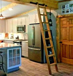 a ladder is hanging from the ceiling in a kitchen with white cabinets and stainless steel appliances