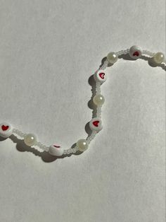 a beaded necklace with hearts and pearls on it's sides is laying on a white surface