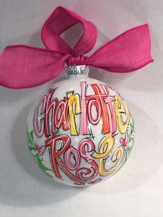 a christmas ornament with the word charlotte rose painted on it and a pink ribbon