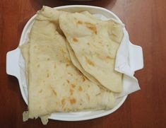 two tortillas sitting on top of a white plate next to a bowl of salsa