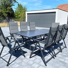 an outdoor table and chairs set up on a brick patio with a garage in the background