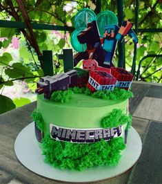 a birthday cake with green frosting and minecraft decorations on the top, sitting on a table outdoors