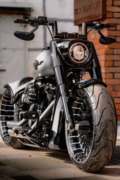 a black and silver motorcycle parked in front of a brick building with its lights on