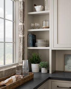 a kitchen with white cabinets and black counter tops, along with a basket on the window sill