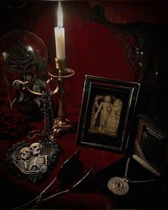 a table topped with pictures and a lit candle next to a framed photo on top of a red cloth