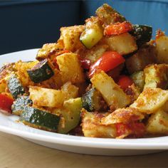 a white plate topped with fried vegetables on top of a wooden table