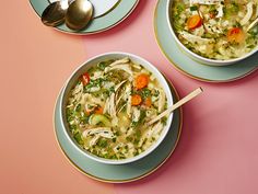 two bowls of chicken noodle soup on a pink and blue table