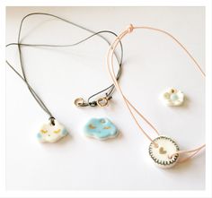 three necklaces with different designs on them sitting on top of a white table next to each other