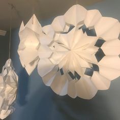 two paper flowers hanging from the ceiling in a room with blue walls and white decorations