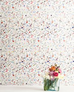 a vase filled with flowers sitting on top of a white table next to a wall