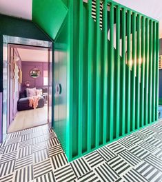 a room with green partitions and black and white tiles on the floor, along with an open door