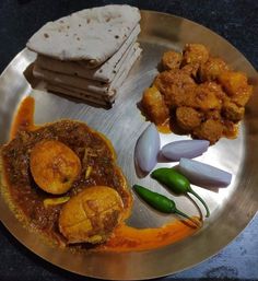 a silver plate topped with different types of food on top of a table next to bread