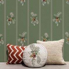 two pillows and a pillow on the floor in front of a wallpapered background