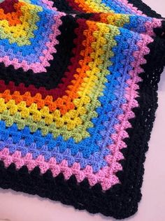 two crocheted squares on top of each other, one is multicolored