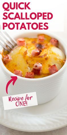 a white plate topped with potatoes covered in cheese and bacon next to a fork on top of it