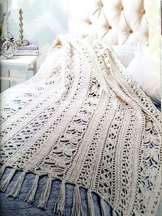 a white crocheted blanket sitting on top of a bed