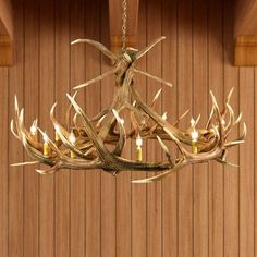 a deer antler chandelier hanging from a wooden ceiling with candles in it