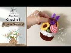 a crochet flower basket hanging on the wall next to a hand holding it