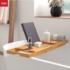 a bath tub with a wooden tray on the side and various items in front of it