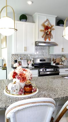 a kitchen with white cabinets and marble counter tops is pictured in this image, there are two chairs at the center of the island