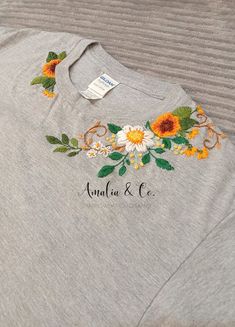 a gray shirt with flowers on it and the name analua & co written in white