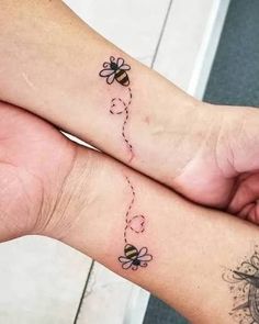 two people with matching tattoos on their feet, one has a bee and the other has a flower