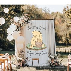 a winnie the pooh baby shower sign with balloons and streamers in the background