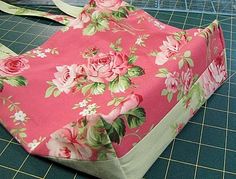 a pink flowered bag sitting on top of a table next to a pair of scissors