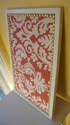 a red and white wall hanging on the side of a window sill in a room