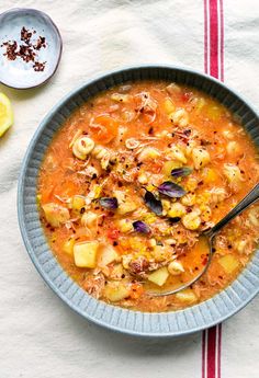 a bowl filled with soup next to two spoons on top of a white table cloth